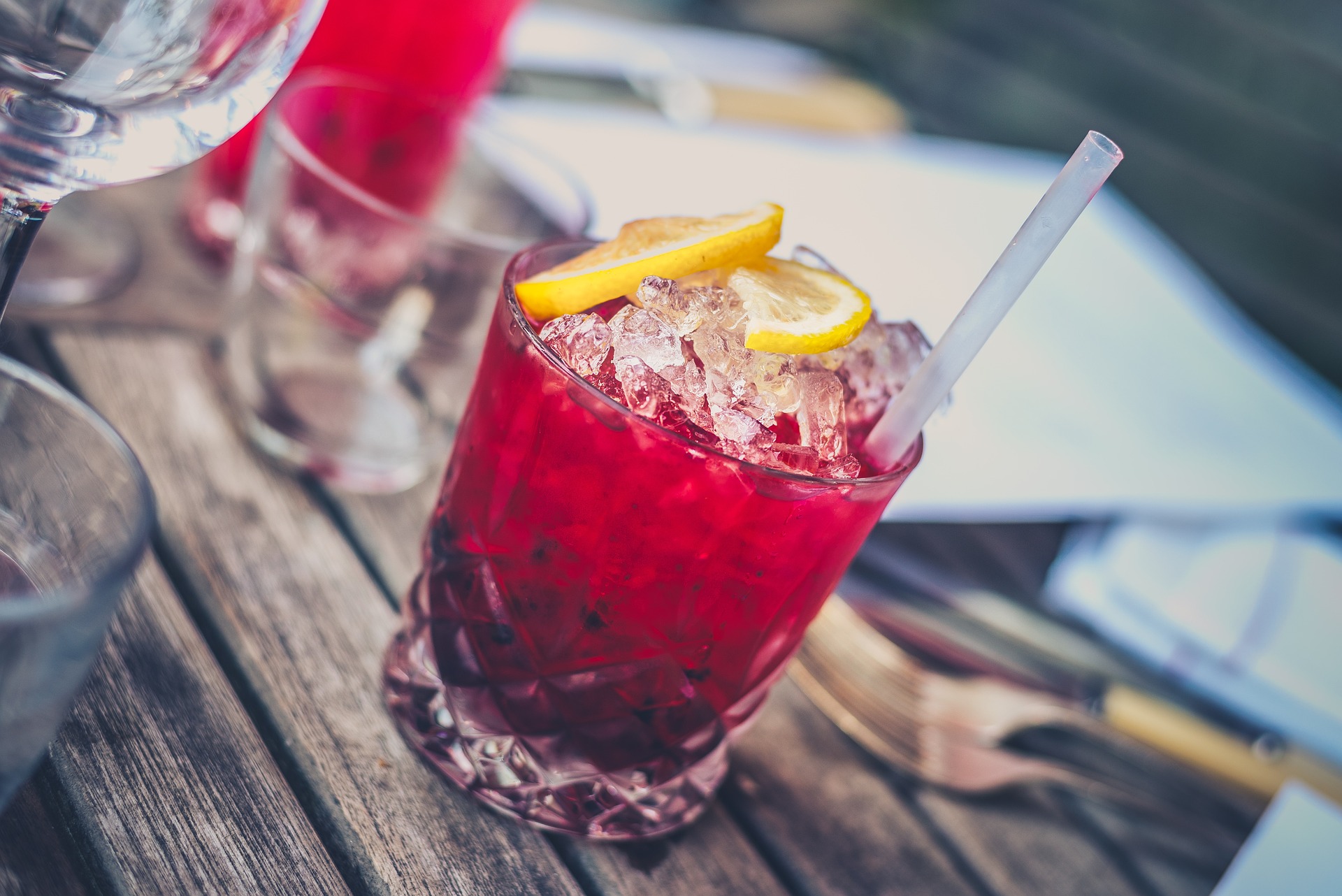 Roter Cocktail mit Eis, Zitrone und Strohhalm