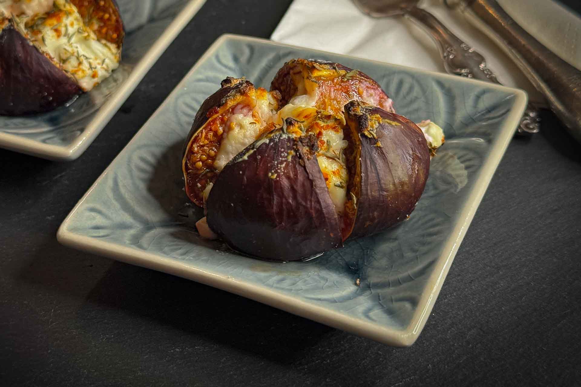 Feige mit Ziegenkäse überbacken, mit Thymian auf einem kleinen, grauen Teller