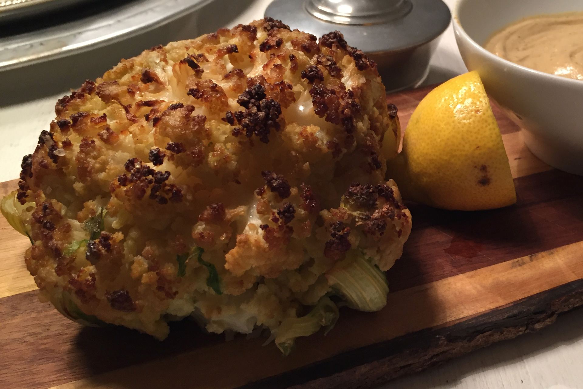 Im Backrohr gerösteter Karfiol mit einer Zitrone auf einem Holzbrett