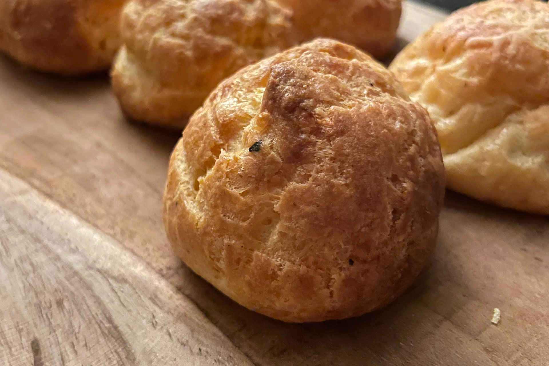 Fluffige Gougéres mit würzigem Bergkäse auf einem Holzbrett