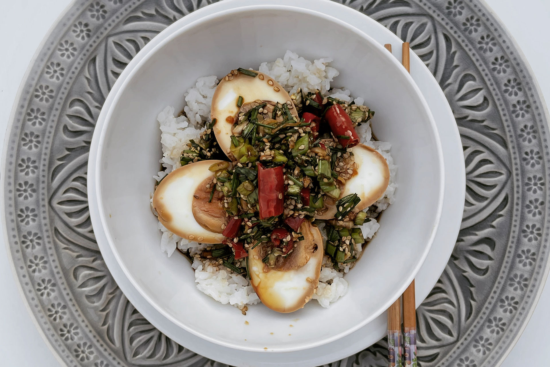 in Sojasauce und Gewürzen wie Frühlingszwiebel, Zucker, Chili und Sesam marinierte Hühnereier auf Reis in einer Schale