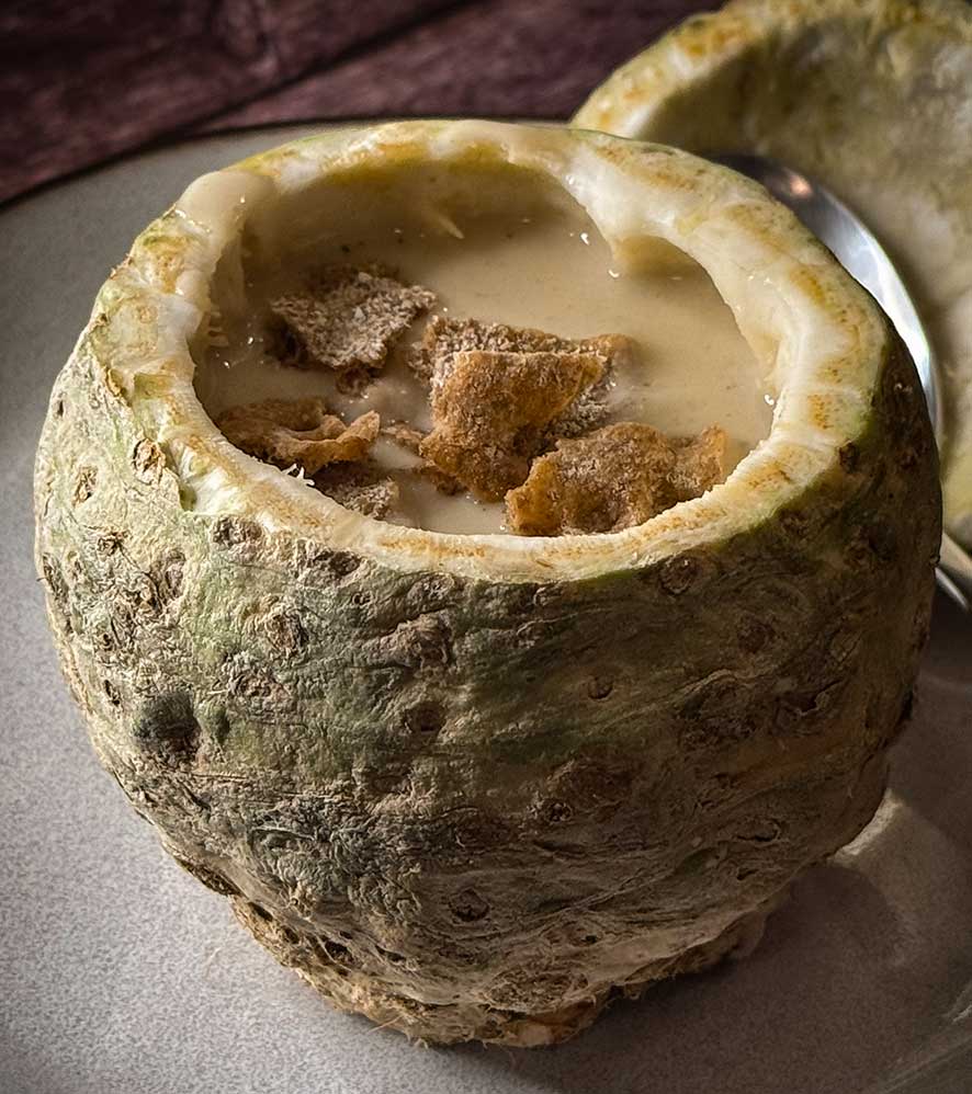 Selleriecremesuppe serviert im ausgehöhltem Knollensellerie, dazu Croutons aus Schwarzbrot